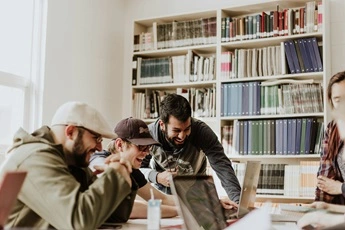 team happily working on a project, bookshelf in background